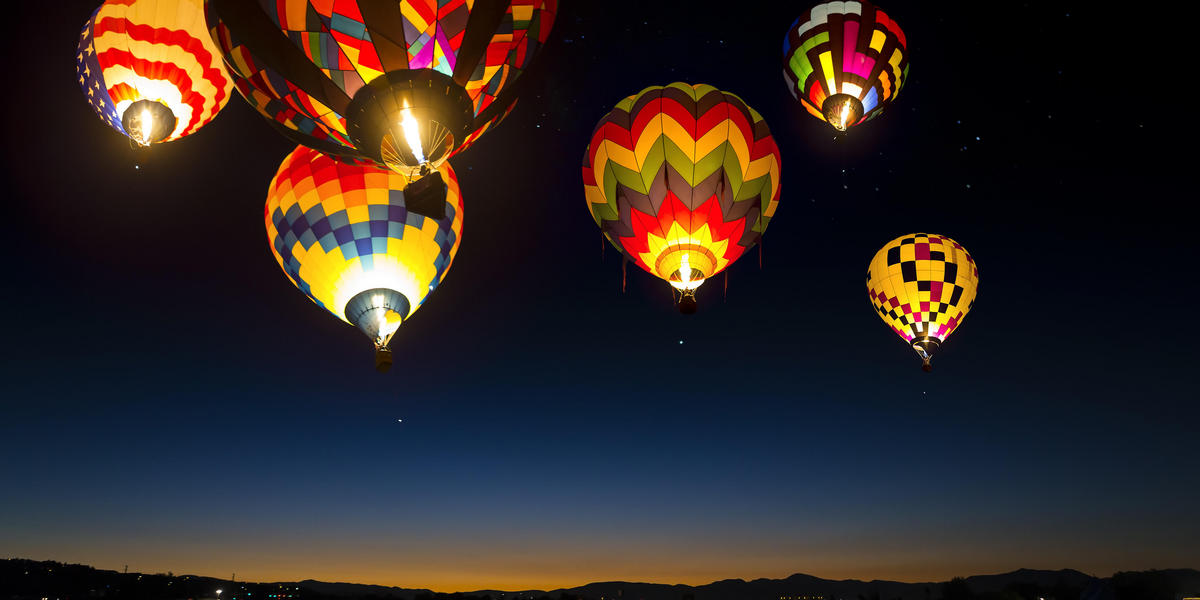 Hot air balloons in flight and lit up in night sky