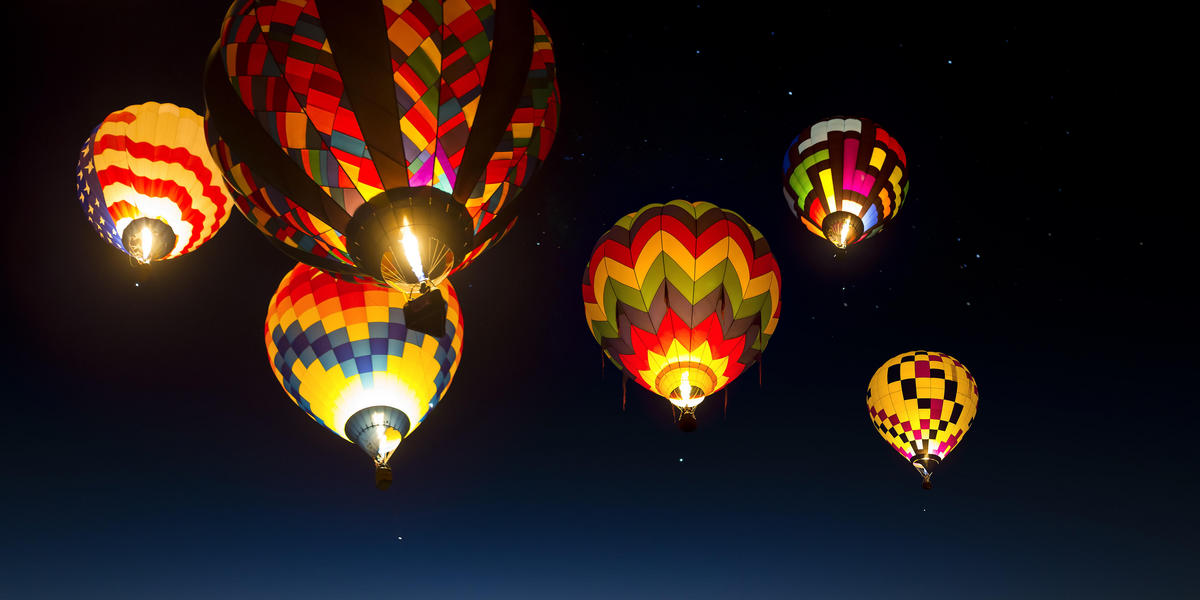 Hot air balloons in flight and lit up in night sky