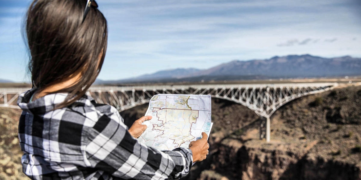 Woman holding map while facing Rio Grande Gorge