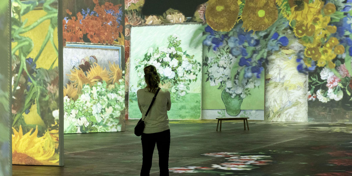 Person viewing floral digital floral paintings in Beyond Van Gogh Experience